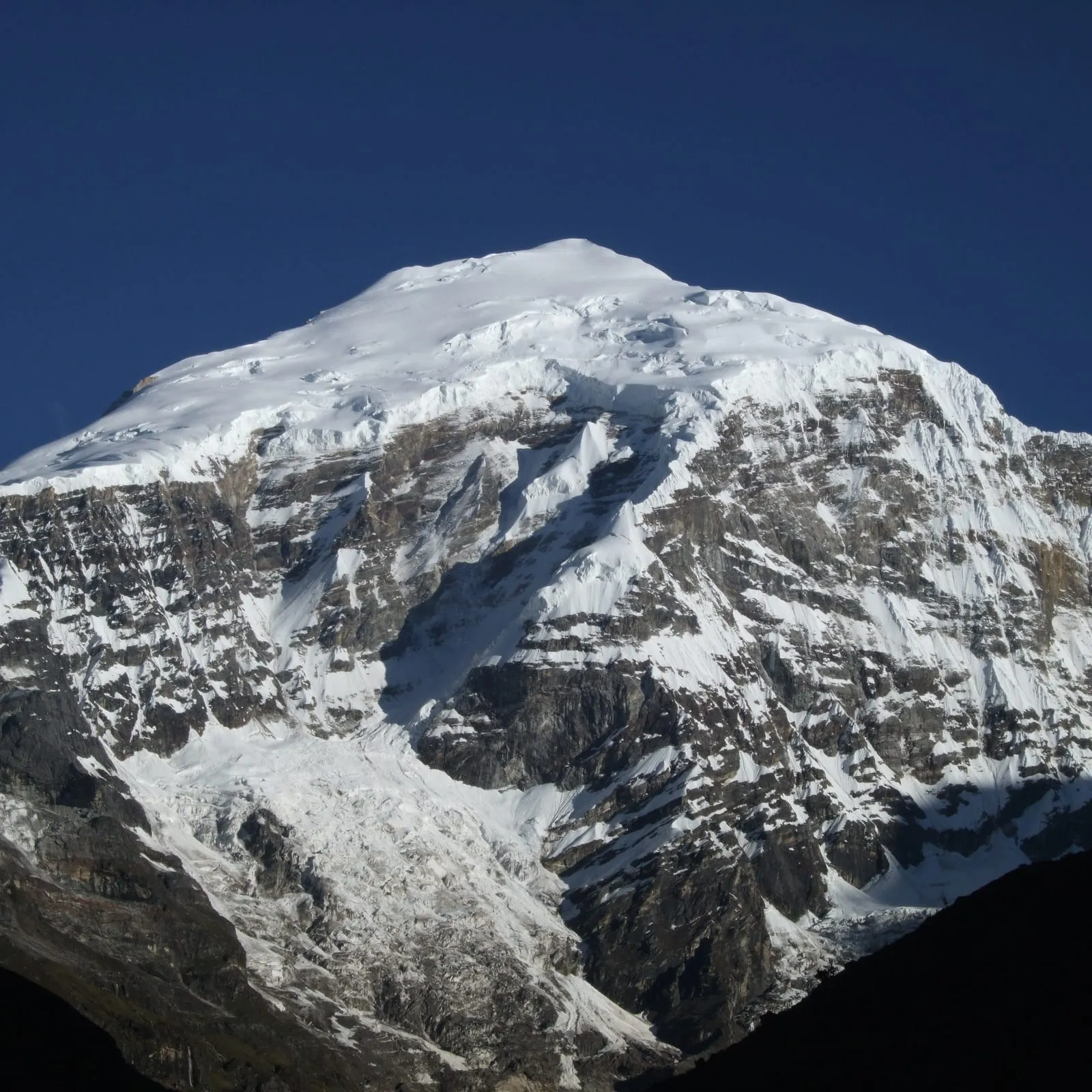The summit face of Jomolhari under a deep blue sky
